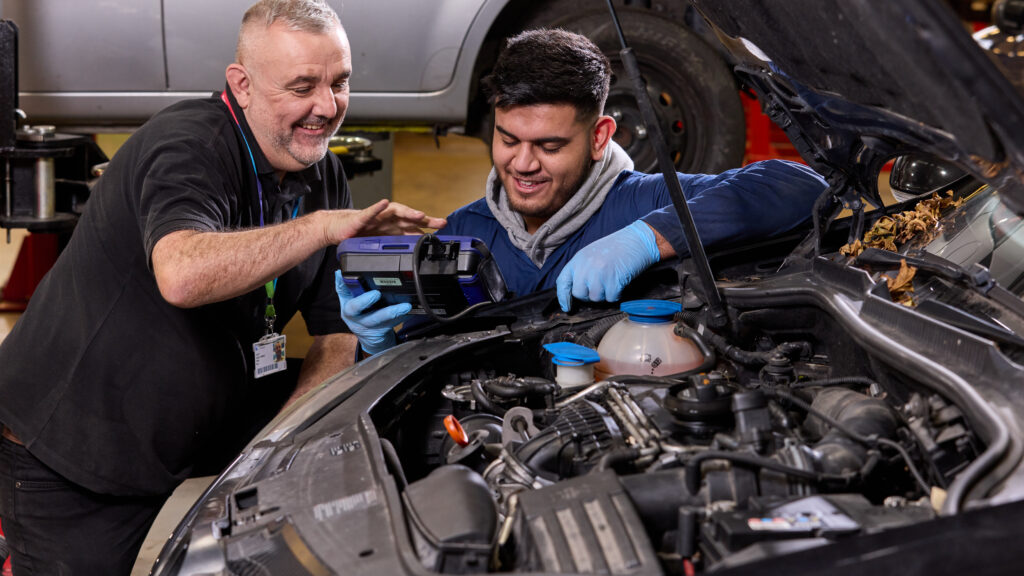 Photo of a student and tutor working together on a car engine