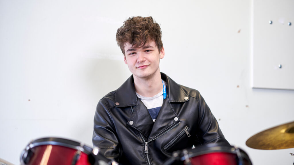 Photo of student Sam Simmons sat behind a drum kit
