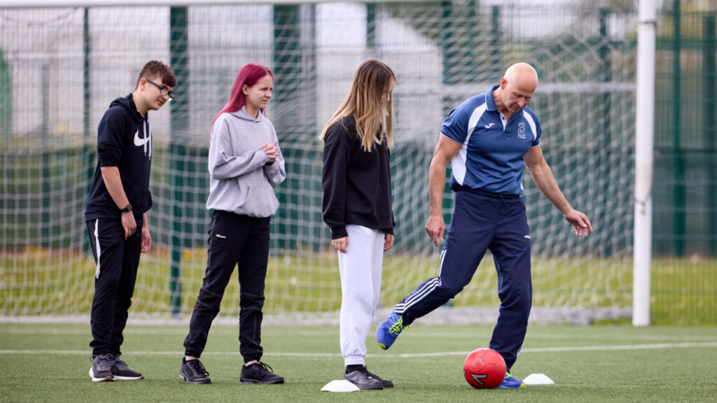 Photo of a trainer with students on a football pitch