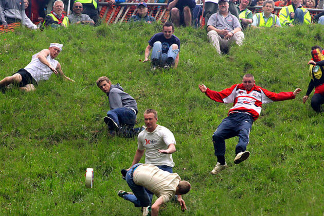 People chasing chesse down a hill.