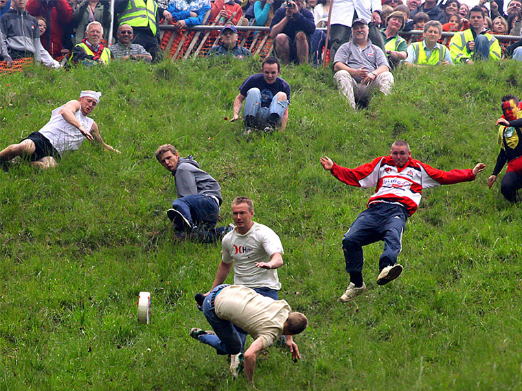 People chasing chesse down a hill.