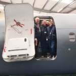 Three members of staff standing in doorway of flight simulator