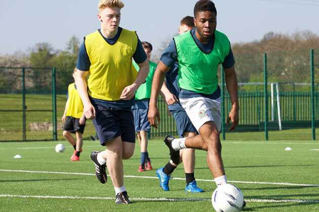 Some male students playing football.