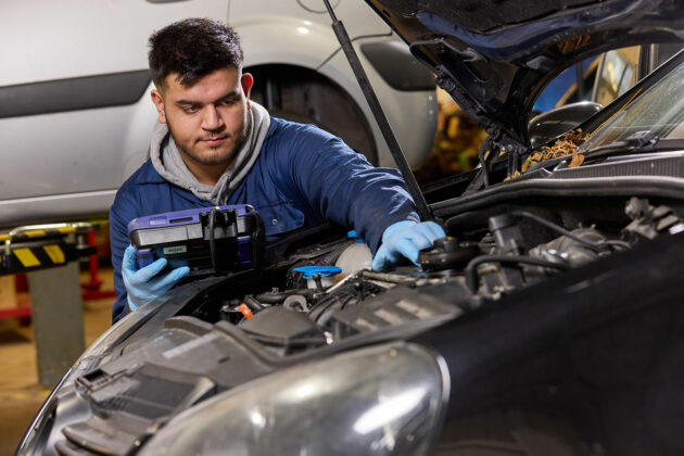 A motor vehicle student working under a car's bonnet