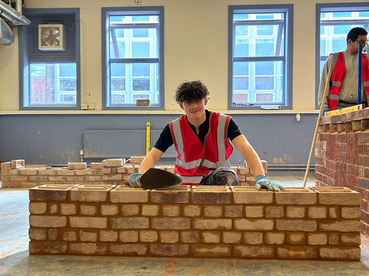 A student building a brick wall