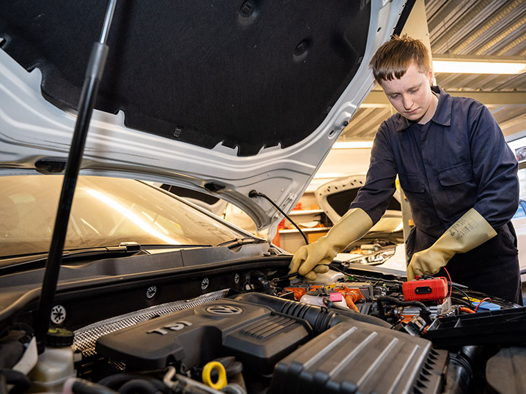 A learner looking under a car bonnet in the motor vehicle department