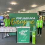 Two student ambassadors stood next to a large Futures For Everyone banner