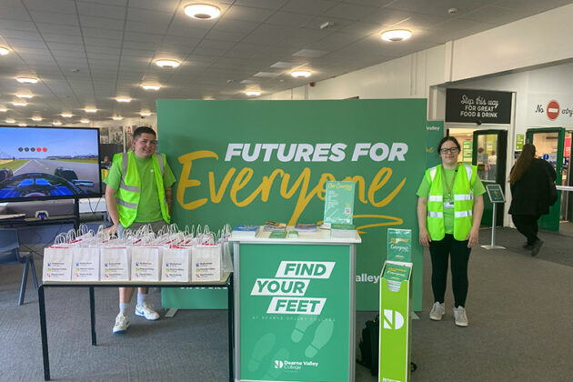 Two student ambassadors stood next to a large Futures For Everyone banner