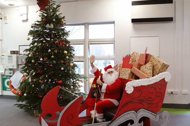 Santa sat in his sleigh with a Christmas tree in the background