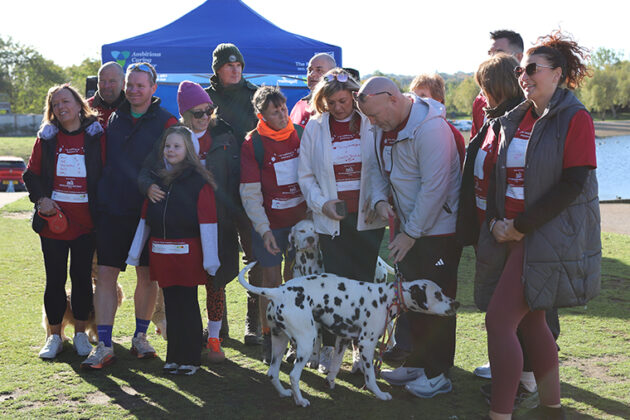 A group of people stood together with two Dalmations, a blue gazebo in the background